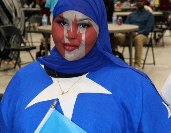 Somali girl wearing Somali flag clothing with Canadian flag painted on her face